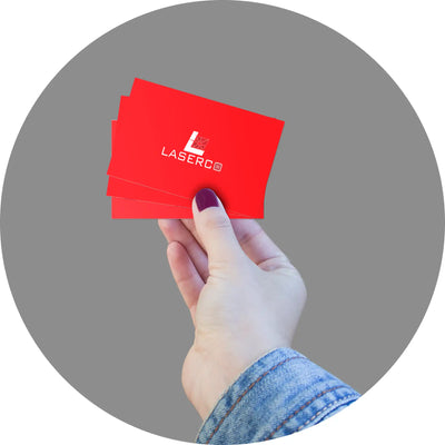 Red business card being held by a hand wearing denim.